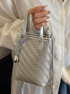 Silver woven crossbody phone bag with metallic finish and heart-shaped metal charm