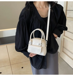 Polished white mini crossbody bag with glossy finish and silver hardware on female model