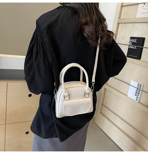 Detail of a creamy white leather mini crossbody bag styled with a modern outfit
