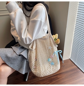 Close-up of beige knitted mesh tote bag featuring colorful starfish and ribbon details