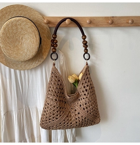 Detail of woven straw tote bag with decorative wooden beads and hollow geometric patterns