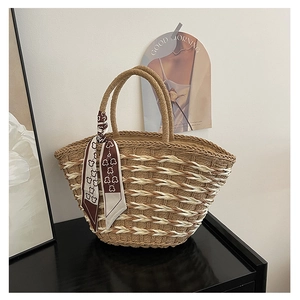 Detailed macro view of handcrafted straw weave pattern and silk scarf handle on tote