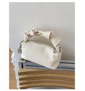 Detail view of cream white leather bag with knot handle and silver ball charm