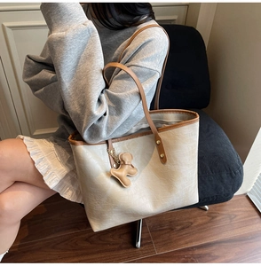 Detail of cream crocodile embossed leather tote bag with brown straps and bear charm
