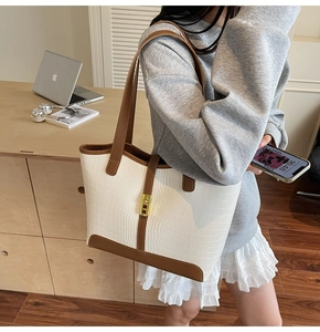 Detail showing white crocodile pattern tote bag with brown straps and golden metal lock