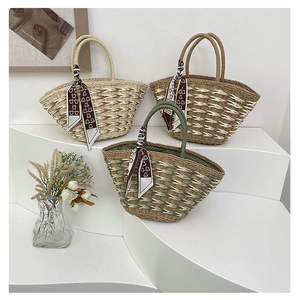 Detailed view of three handmade woven straw tote bags with floral scarves on white background