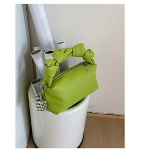 Detail of green lychee leather handbag featuring a knot handle and silver beaded charm