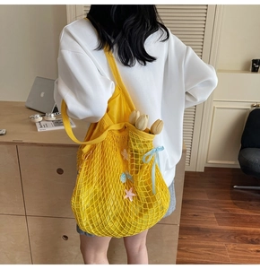 Detailed view of yellow mesh tote bag with star patches and blue ribbon detail on a model