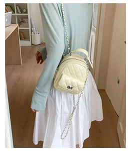 Detail of light yellow quilted mini backpack with silver chain strap and top handle