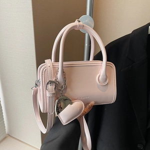 Detail of light pink PU leather bowling bag with heart charm and detachable shoulder strap