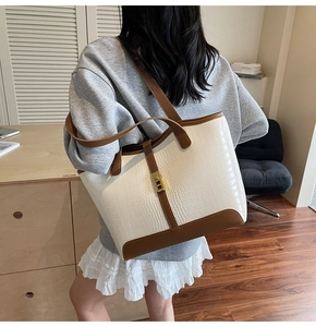 Model showing white croc-textured tote bag with brown leather trim and gold metal lock