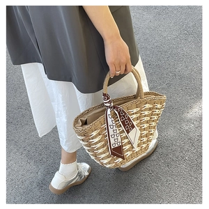 Close-up of handmade straw tote bag with white stripes and a decorative silk scarf