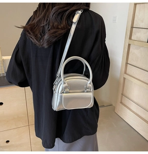 Mini silver metallic handbag with shoulder strap worn by a model in a cozy indoor setting
