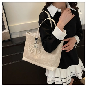 Detail of elegant beige floral jacquard tote bag with stylish daisy charm pendant