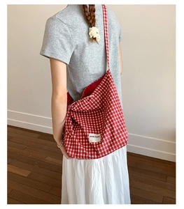 Close-up of red and white checkered canvas tote bag with embroidered logo label