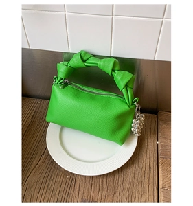 Detail of lime green leather handbag with unique knotted handle and silver bead pendant