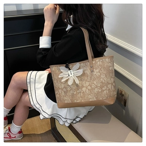 Floral canvas tote bag with brown leather trim and flower charm shown on model