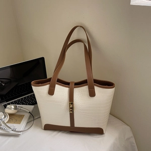 Minimalist tote bag with crocodile texture and gold hardware on a desk with laptop
