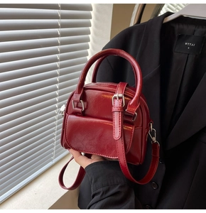 Detail of dark red vintage faux leather handbag with silver buckle pocket and top handle