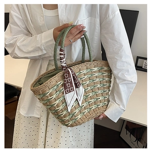 Detailed macro view of woven straw tote bag with green wave pattern and bear print silk scarf