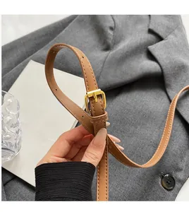 Detail view of brown leather shoulder strap with gold buckle on vintage print mini bag