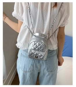 Silver quilted mini backpack with metal chain straps shown on a model's back