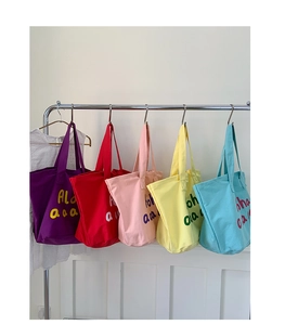 Detailed view of colorful canvas tote bags with Aloha print hanging in five bright colors