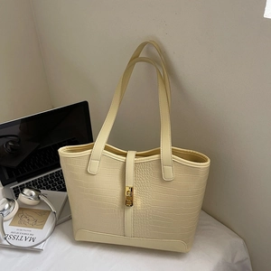 Detailed macro view of cream crocodile embossed leather tote bag with gold metal clasp