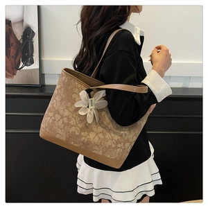 Detail of floral print tote bag featuring thin leather straps and a white flower charm