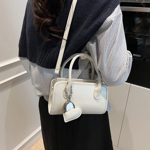 Close-up of white PU leather bowling bag with silver chain and heart charm detail