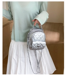 Detail shot of a silver quilted mini backpack with metal chain strap and turn-lock closure