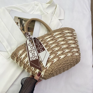 Close-up of handmade straw tote bag with brown stripes and decorative silk scarf