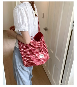 Detail view of red gingham tote bag featuring OUR FAVE text label and canvas texture