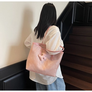Detail of pink croc-embossed tote bag with puppy charm on a model in casual attire