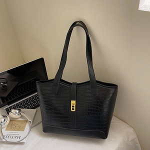 Close-up of black crocodile pattern tote bag with gold buckle and office supplies