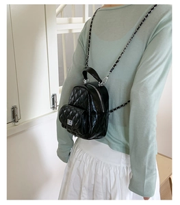 Detailed view of black quilted faux leather mini backpack with chain strap and metal lock