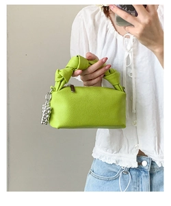Detailed view of neon green pleated handbag with silver bead charm and knot handle