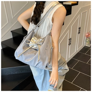 Detail of silver pleated fabric tote with 3D bow and drawstring on a model