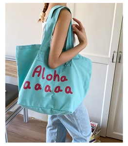 Detail of light blue canvas tote bag featuring red Aloha print with sturdy fabric handles