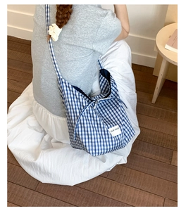 Detail of blue and white gingham canvas tote bag with a minimalist woven label