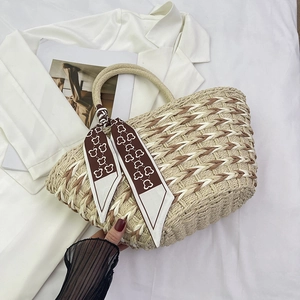 Detail of handmade straw bag with woven pattern and decorative brown bear print scarf