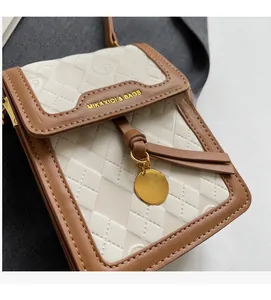 Detailed close-up of brown leather and embossed fabric bag with gold tassels