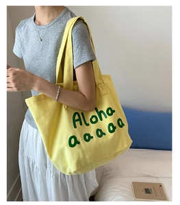Close-up of bright yellow canvas tote bag with green Aloha print and dual handles