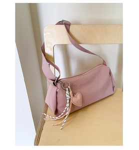 Detailed shot of a pink nylon crossbody bag with heart pendant and striped rope charm