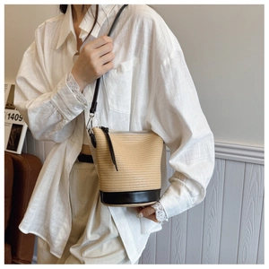 Vue détaillée du sac seau en paille tressée avec base en cuir noir et bandoulière