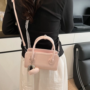Pink PU leather bowling handbag featuring embossed logo and cute heart-shaped charm accessory