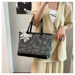 Close-up of floral fabric tote bag with leather straps and white flower charm accessory