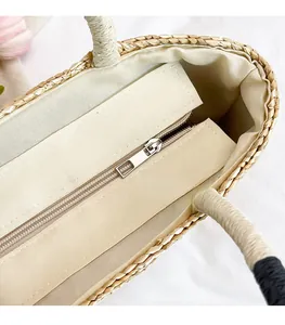 Detailed top view showing the metal zipper closure and beige canvas lining of the straw tote bag