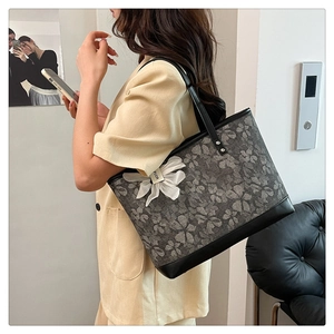 Detail of grey floral tote bag with black leather trim and white fabric flower charm