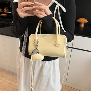 Detail of light yellow bowling bag featuring heart charm and adjustable shoulder strap